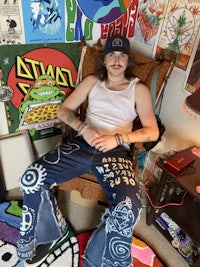 a man laying on a chair in a room with a lot of posters