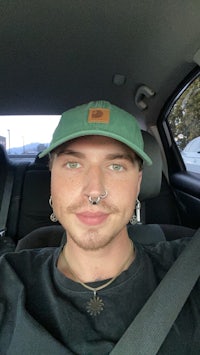 a man wearing a green hat and piercings