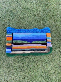 a blue and orange striped blanket laying on the grass